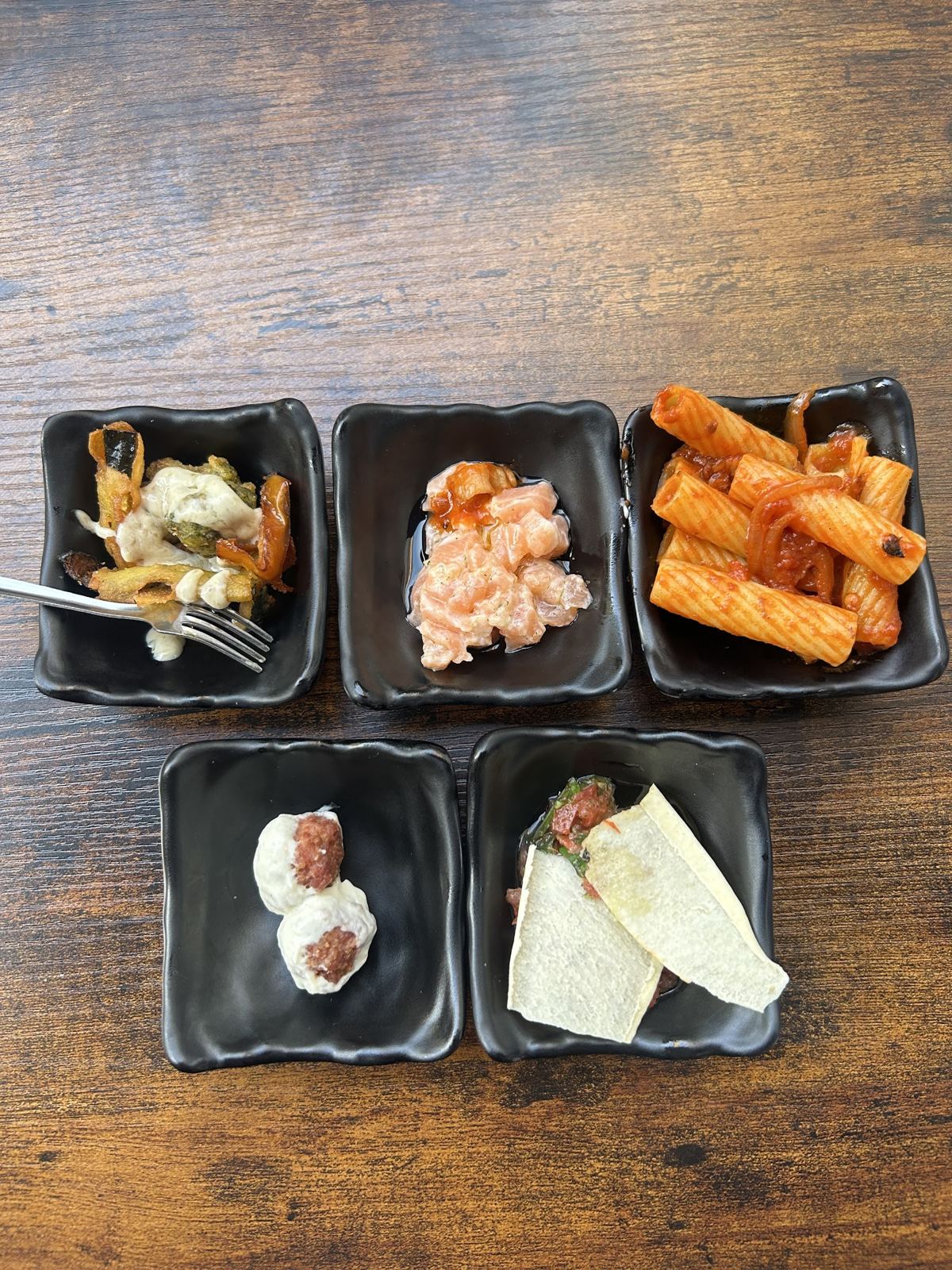 Tray with five little bowls of tapas: pasta, prawns, meatballs, mozzarella