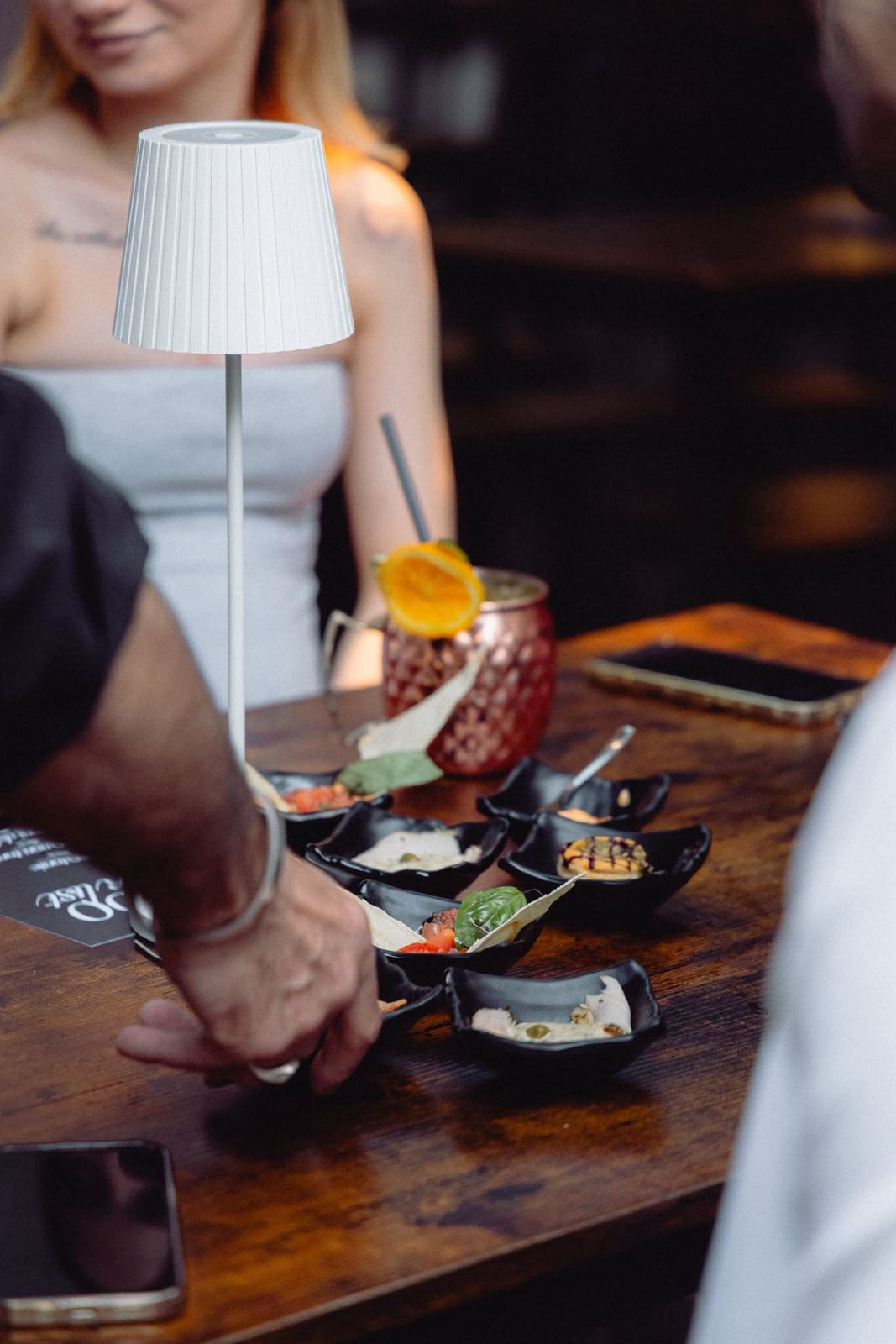 Tavolo con la lampada accesa, cocktail e vassoi di tapas